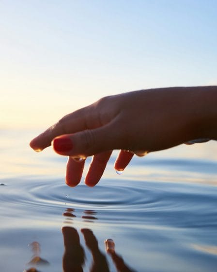 person about to touch the calm water